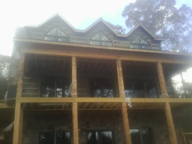 Dormers and porch framing on a large log home under construction — Roof Coating work by our crew in Hawthorne