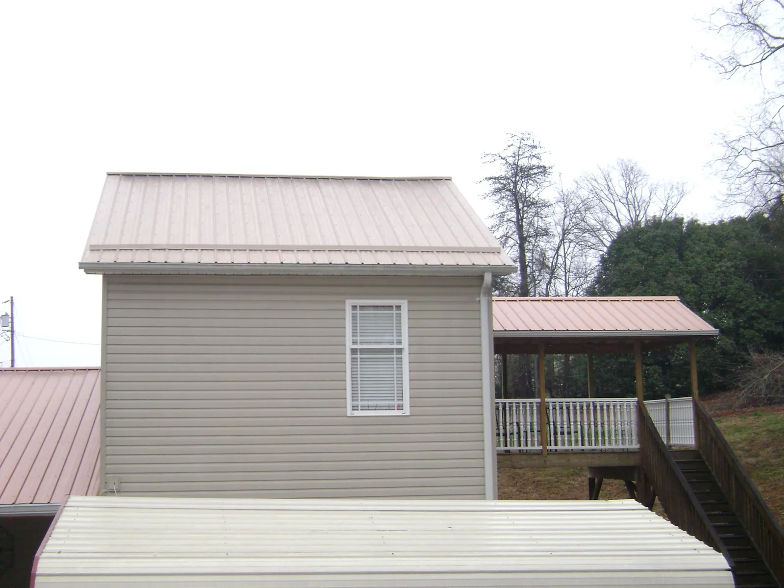 Tan metal roofs on a two story addition and attached porch, from a Roof Replacement job in Hawthorne