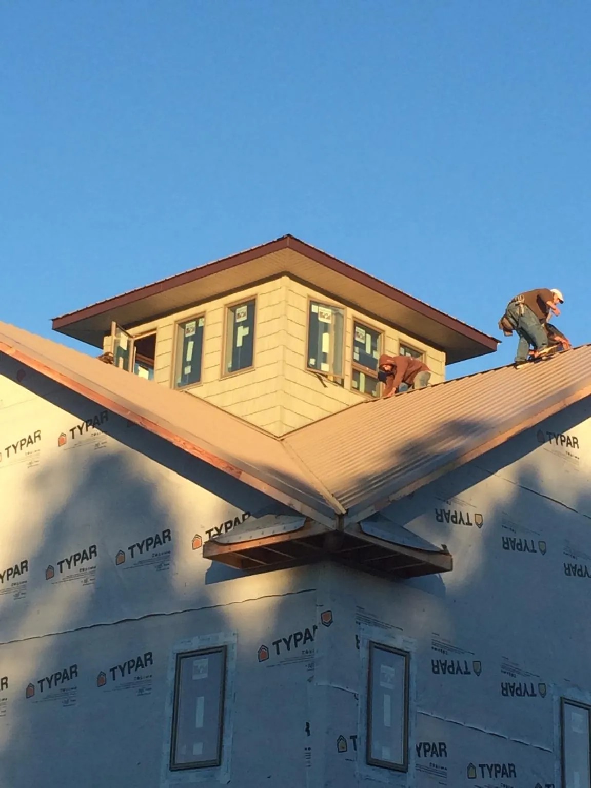 Roofers working around a rooftop cupola on a new metal roof at sunset — Roof Waterproofing in Hawthorne by Roofing Brothers